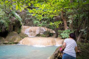 young cute hipster girl travelling at beautiful Erawan waterfall mountains 
green forest hiking views at Kanchanaburi, Thailand. guiding 
idea for female backpacker woman women backpacking