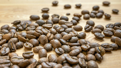 Roasted coffee beans randomly dumped on a wooden table-Close up