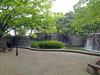 Two people are resting on bench in picturesque park with decorative waterfalls. The girl and the guy are talking. Seoul, South Korea.