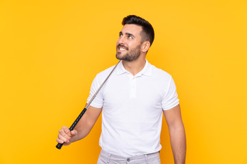 Man over isolated yellow background playing golf