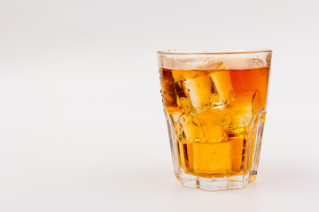 Glass of scotch whiskey and ice over white background.