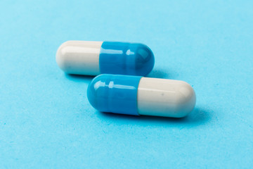 Pills isolated on blue background. Medical drug capsule. Concept of coronavirus