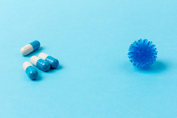 Pills isolated on blue background. Medical drug capsule. Concept of coronavirus