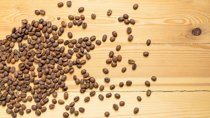 Roasted coffee beans randomly dumped on a wooden table