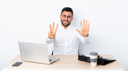 Young businessman in a workplace counting eight with fingers