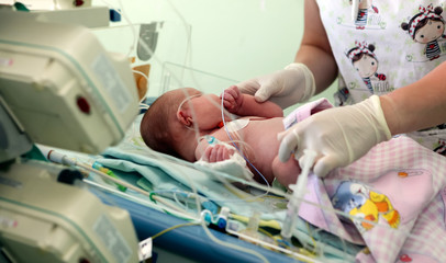 young female nurse holding a newborn baby in hospital - obrazy, fototapety, plakaty
