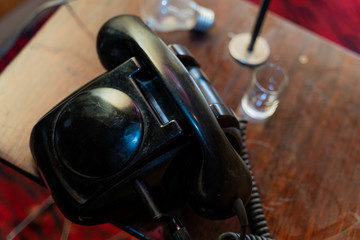 Stary czarny telefon, w tle żarówka i kieliszek
