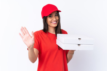 Pizza delivery woman holding a pizza over isolated white wall saluting with hand with happy expression