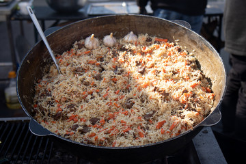 Cooking of traditional pilaf in big cauldron, street food in outdoor