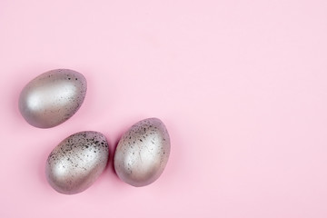 Three easter silver eggs on pink background with copyspace