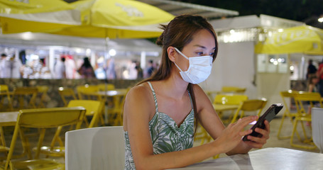 Woman wearing face mask with cellphone at outdoor night market