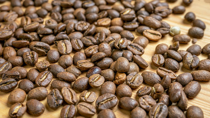 Roasted coffee beans randomly dumped on a wooden table-Close up