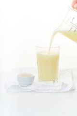 Dairy alternative. Rice milk pouring in a high glass on white background.