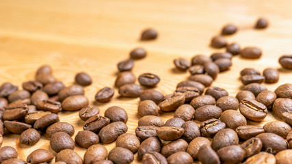 Roasted coffee beans randomly dumped on a wooden table-Close up