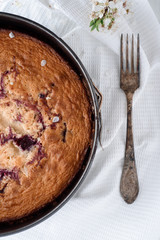 Cherry pie on a white wooden background. Nearby is an old silver spoon and spring flowering.