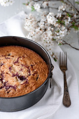 Cherry pie on a white wooden background. Nearby is an old silver spoon and spring flowering.