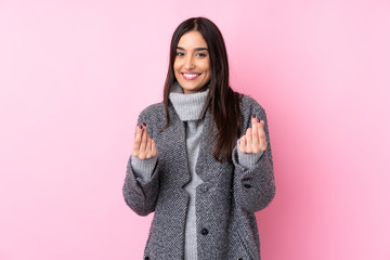 Young brunette woman over isolated pink background making money gesture