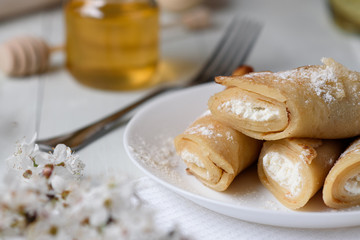 Pancakes with cottage cheese on a white wooden background. Shot with honey, sunflower seeds, flour and eggs. A traditional breakfast.