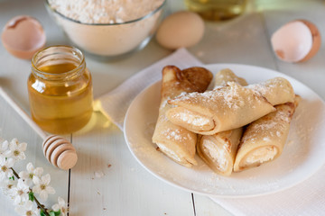 Pancakes with cottage cheese on a white wooden background. Shot with honey, sunflower seeds, flour and eggs. A traditional breakfast.