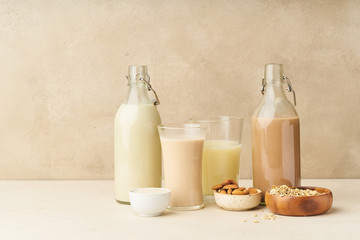 Dairy alternative. Rice, oat, cashew and chocolate almond milk in bottles and glasses on beige background. Healthy protein vegan drink.