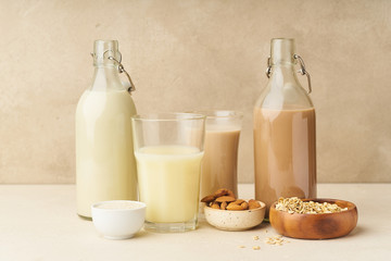 Dairy alternative. Rice, oat, cashew and chocolate almond milk in bottles and glasses on beige background. Healthy protein vegan drink.