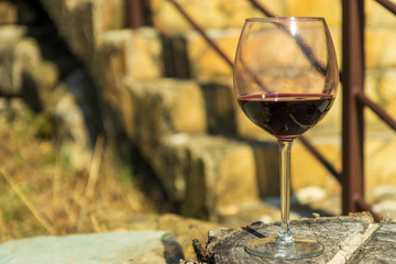 Glass of red wine on the wooden stump with stairway on the background