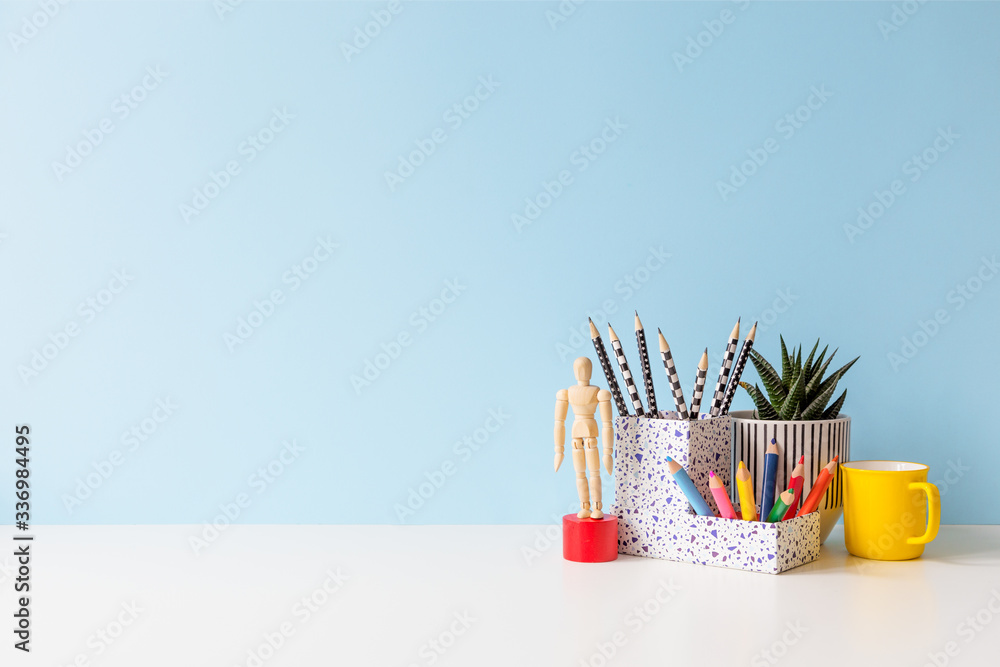 Wall mural Desk with colorful school supplies and blue wall background. Back to school.