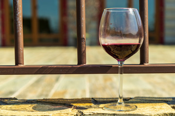 Glass of red wine on the wooden floor with chalet behind