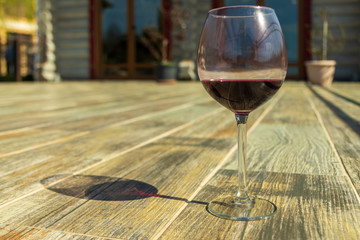 Glass of red wine on the wooden floor with chalet behind
