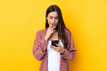 Young brunette woman over isolated yellow background thinking and sending a message