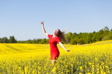 Naklejka premium Happy young woman in a red dress in the rape field