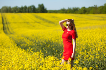 Naklejka na ściany i meble Happy young woman in a red dress in the rape field