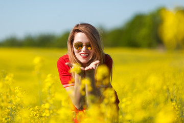 Happy young woman in a red dress in the rape field