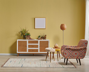 Yellow living room wall and wicker cabinet, orange lamp and frame style with chair.