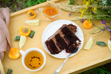 Summer picnic, a slice of chocolate cake and fragrant tea with wildflowers on the table