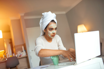 Woman working from home, using laptop in quarantine. Woman wears beauty mask working from home at the computer during self-isolation and quarantine. Coronavirus outbreak and flu covid epidemic.