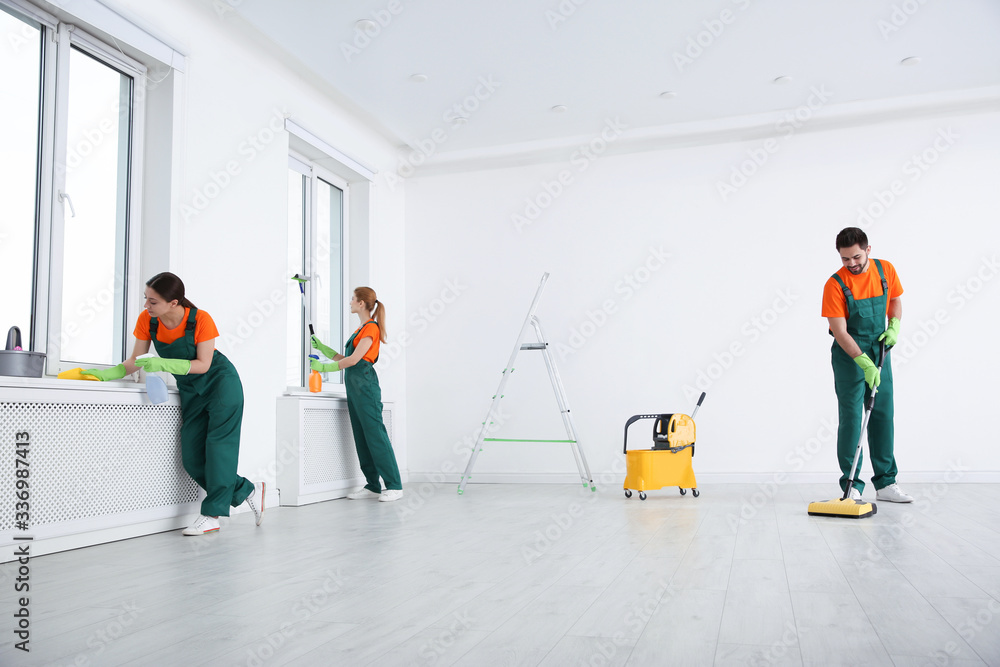 Wall mural Team of professional janitors in uniforms cleaning room