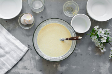 Thin homemade pancakes. Thin pancake recipe. Light concrete background. Top view. Cooking step by step traditional pancakes. Ingredients. Cooking. Hands in the frame