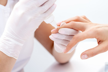 Manicure specialist applying glue for nail of woman close up. Manicurist uses manicure tool.