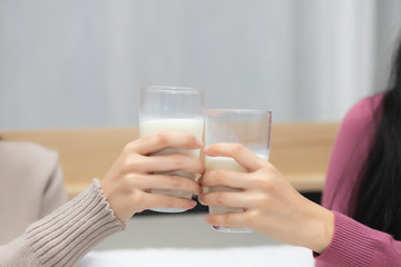 Two people bumping a glass of milk into the bedroom In the concept of drinking milk before bed to stay healthy and strong