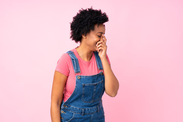 African american woman with overalls over isolated pink background laughing