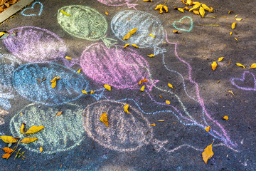 Child's chalk drawing of balloons on asphalt