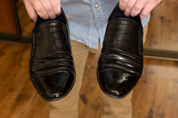 Classic black patent leather male shoes in hands of man