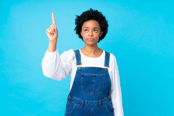 African american woman with overalls over isolated blue background touching on transparent screen