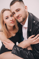 Beautiful young couple in studio standing back to back. Man wearing in denim clothes and lizard jacket. Beautiful young sexy girl in black bodysuit and shoes.