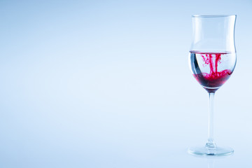 Wine glass of water with red color drop.