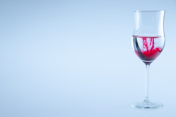 A glass of water with red color drop.