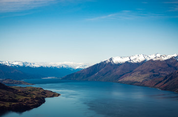 Stunning aerial image of the Wanaka lake with the snowy Mount Aspiring in the background on a sunny winter day, New Zealand