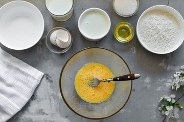 Thin homemade pancakes. Thin pancake recipe. Light concrete background. Top view. Cooking step by step traditional pancakes. Ingredients. Cooking. Hands in the frame