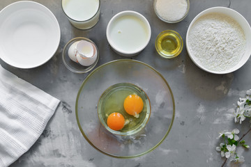 Thin homemade pancakes. Thin pancake recipe. Light concrete background. Top view. Cooking step by step traditional pancakes. Ingredients. Cooking. Hands in the frame